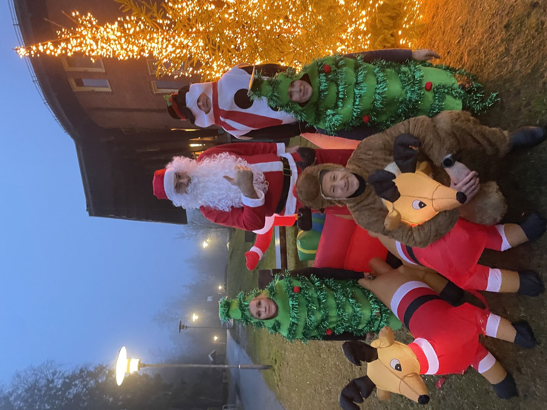 En gruppe mennesker utkledd som julenissen som sitter i en sofa